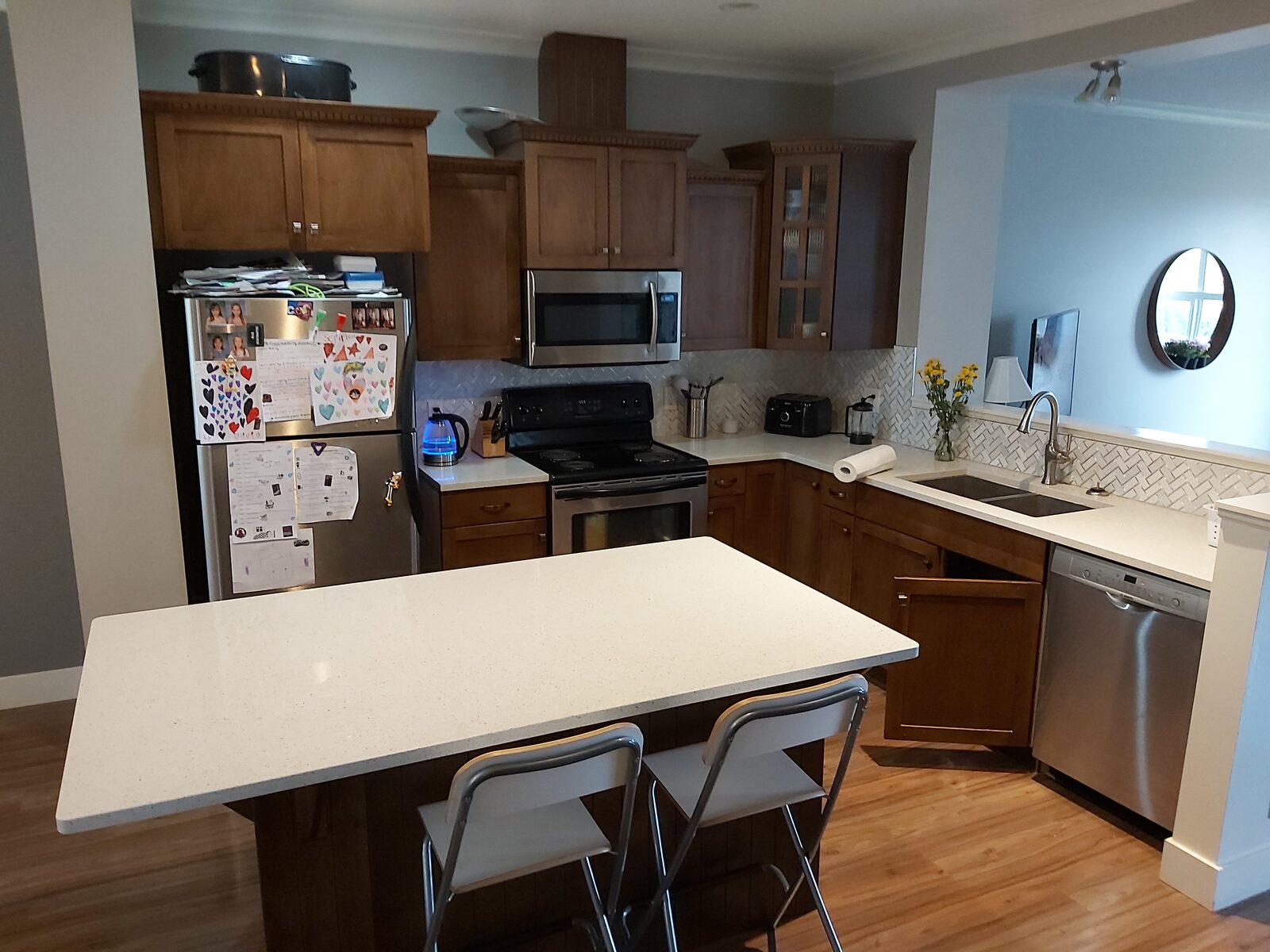 Builder-grade townhouse kitchen before renovation with brown maple shaker cabinets and a gap above the upper cabinets